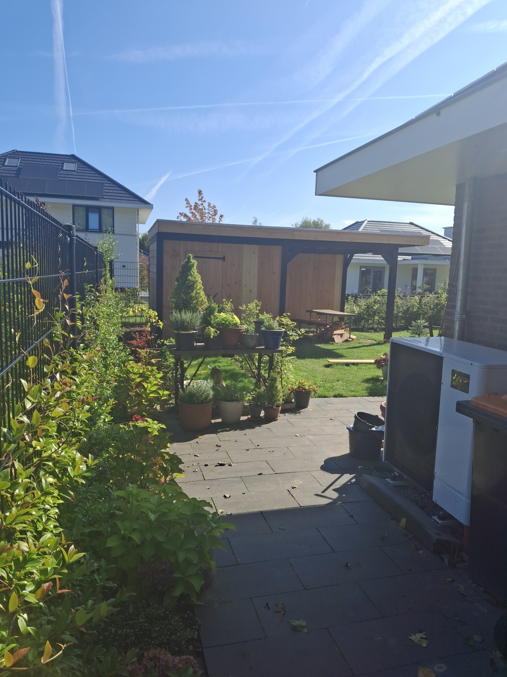 Tuin met een houten bijgebouw achterin, pad aan de zijkant